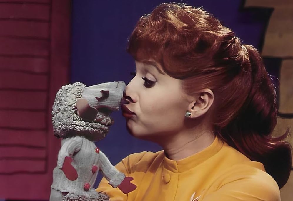 : Ventriloquist Shari Lewis is pictured kissing her puppet, Lamb Chop, on the nose. While the picture is in color, it is from the earlier days of her career.