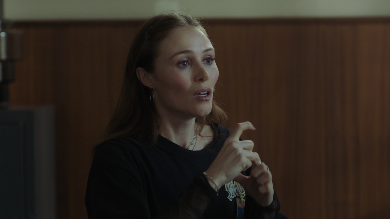 A medium shot from the film “Beyond Silence” of a woman in a dimly lit room signing with her hands.