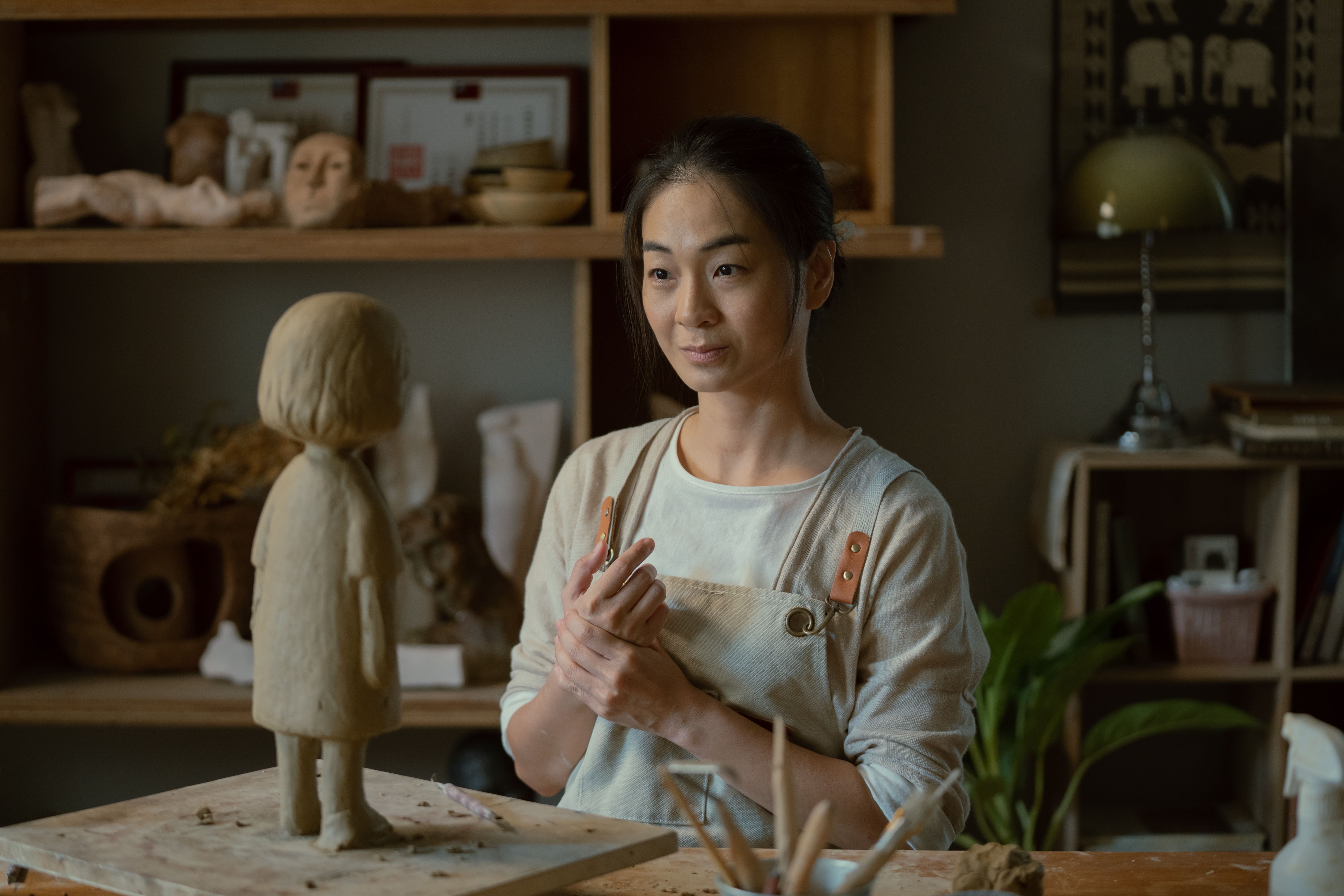 A medium shot from the film “Stills Moving” of a woman admiring a sculpture that she made.