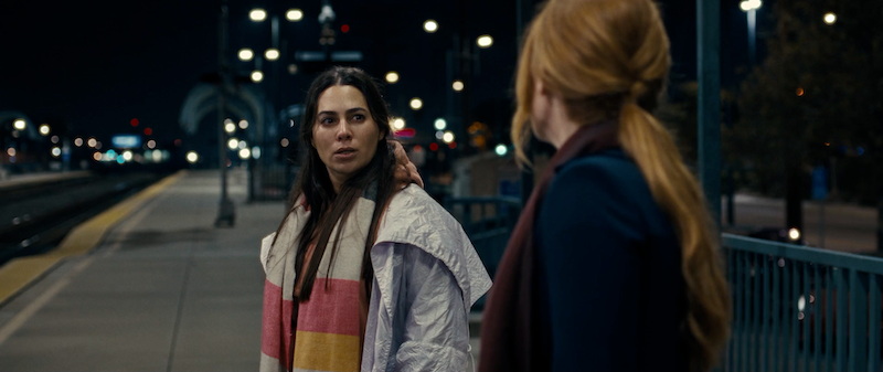 A medium shot from the film “Valentine’s Day” of a woman looking at another woman in a nighttime setting with streetlights in the background.