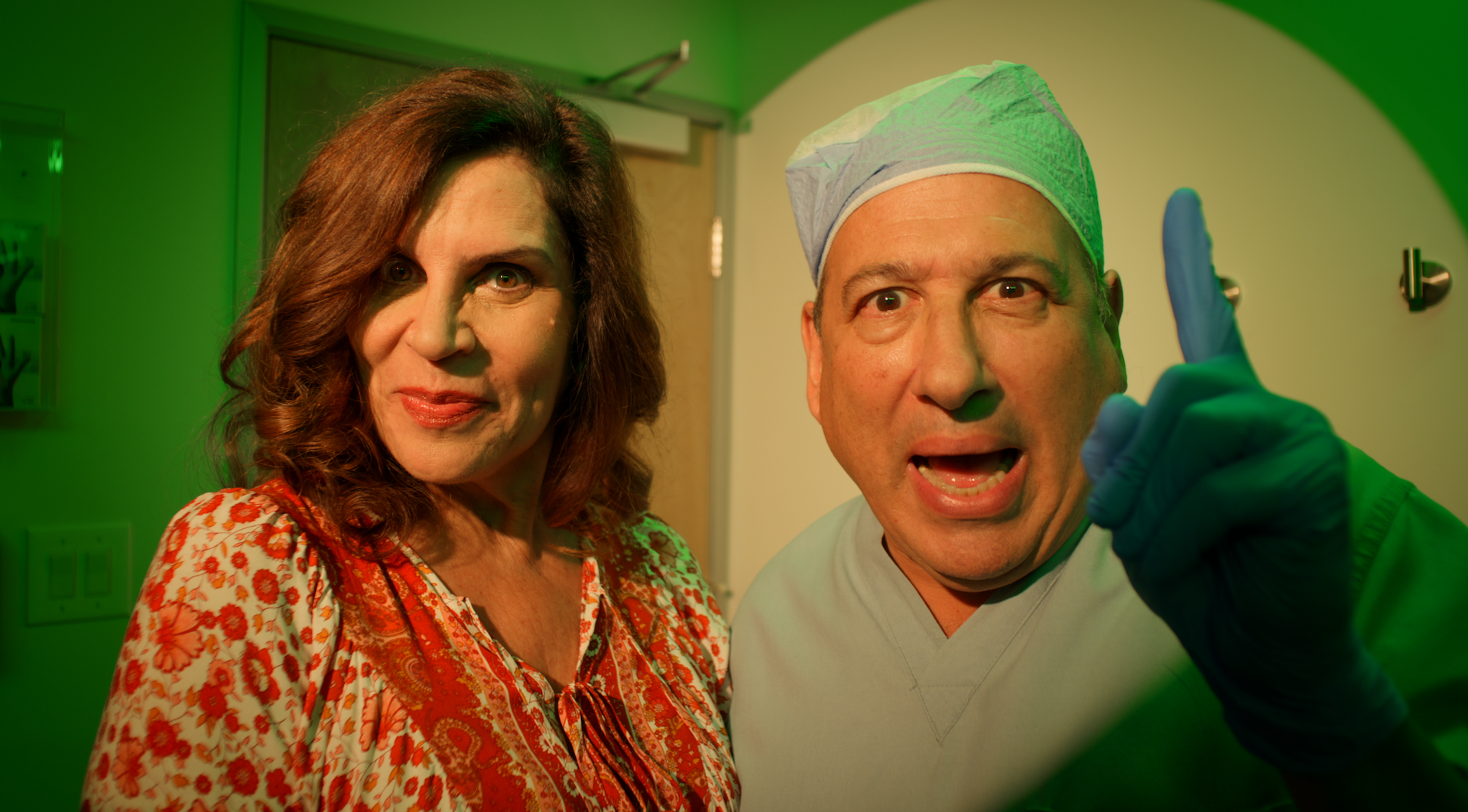 A close up of a woman and a man looking intensely at the camera under vibrant green lighting.